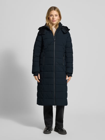 Frauenmodel trägt Steppmantel mit Sorona® Aura Filling von NAUTGÅRD in Schwarz, regular Fit, wasserabweisend, Ganzkörperansicht von vorne.