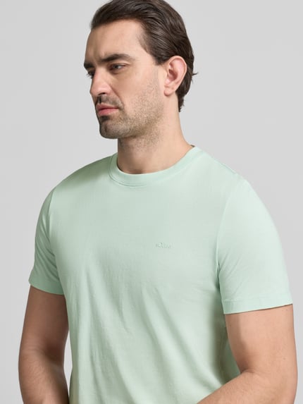 Männermodel trägt Regular Fit T-Shirt aus reiner Baumwolle von s.Oliver RED LABEL in Mintgrün, kurzarm, Rundhals, Nahaufnahme Oberkörper.