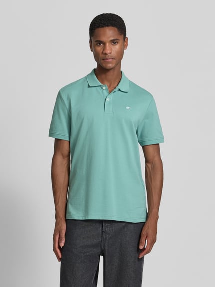 Männermodel trägt Regular Fit Poloshirt aus reiner Baumwolle von Tom Tailor in Mintgrün, glatte Struktur, Ganzkörperansicht von vorne.