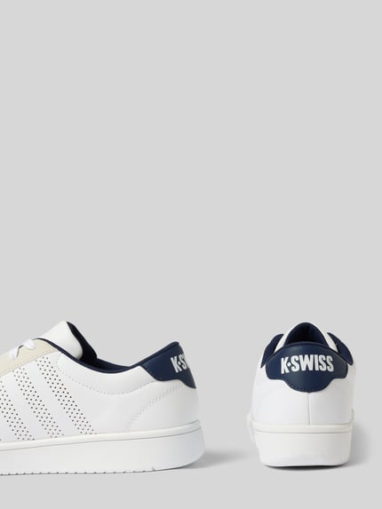 Produktfoto, Sneaker mit Label-Print Modell 'COURT' von K-Swiss in Weiß und Dunkelblau, abgerundete Form, Lochmuster, strukturierte Sohle, Label-Print an der Ferse, Kontext: Herren Sneaker, Schnürverschluss, Absatzhöhe 3 cm, Schafthöhe 7 cm, Schaftweite 10 cm
