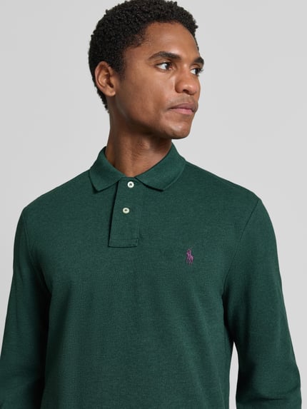 Männermodel trägt Regular Fit Poloshirt aus reiner Baumwolle von Polo Ralph Lauren in Dunkelgrün mit lila Logo, Nahaufnahme Oberkörper, Herren Poloshirt von Polo Ralph Lauren.