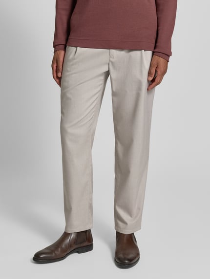 Männermodel trägt Stoffhose mit elastischem Bund von MCNEAL in Beige, lockerer Schnitt, Eingrifftaschen, Tunnelzug, Nahaufnahme Unterkörper.