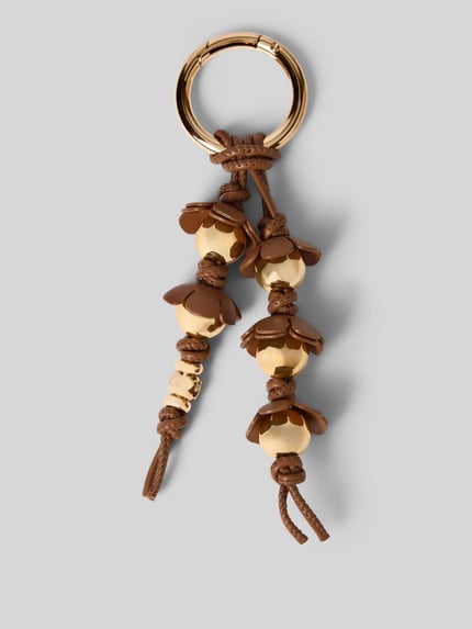 Productfoto, sleutelhanger in bloemenmotief Model 'Novelty' van MICHAEL Michael Kors, glanzend design, logodetail, bruin-gouden kleuren, damesaccessoire