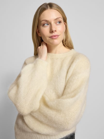 Modelka kobieca nosi Relaxed Fit Strickpullover aus Mohair-Mix Modell 'CAMILLE' od VILLA SOPHIE, kremowy melanż, dzianinowa tekstura, widok z przodu do pasa.