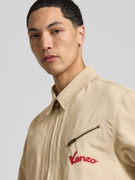 Männermodel trägt Regular Fit Blouson aus reiner Baumwolle von Kenzo in Beige mit Reißverschlusstasche und Label-Stitching, Nahaufnahme Oberkörper, Rückenlänge 66 cm, Schulterbreite 50 cm, Ärmellänge 66 cm.