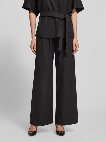 Vrouwenmodel draagt Hose mit weitem Bein und Eingrifftaschen Modell 'Evie Bellevue' van MOS MOSH, zwart, gladde stof, wijde pijpen, Nahaufnahme onderlichaam. Materiaal-mix met viscose, steekzakken, damesbroek.