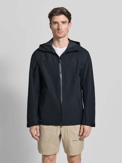 Męski model nosi Regular Fit Jacke mit Logo-Print Modell 'Treeline' od PEAK PERFORMANCE, kolor czarny, krój regular fit, kaptur ze stójką, dwukierunkowy zamek błyskawiczny, kieszenie boczne; długość pleców w rozmiarze M: 73 cm, szerokość ramion w rozmiarze M: 42 cm, szerokość klatki piersiowej w rozmiarze M: 57 cm, długość rękawa w rozmiarze M: 68 cm; widok całej sylwetki z przodu
