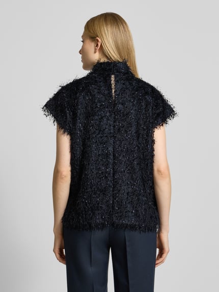Modelka kobieca nosi bluzkę Blusenshirt mit Stehkragen Modell 'ALARIA' od Drykorn, czarny miks materiałów z modalu, luźny krój, strzępienia, widok całej sylwetki z tyłu.