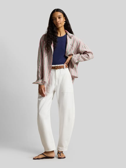 Frauenmodel trägt Boxy Fit Hemdbluse aus reinem Leinen von Polo Ralph Lauren mit rosa-grünem Allover-Streifenmuster, Logo-Stitching, Hemdkragen und einreihiger Knopfleiste, Ganzkörperansicht von vorne.