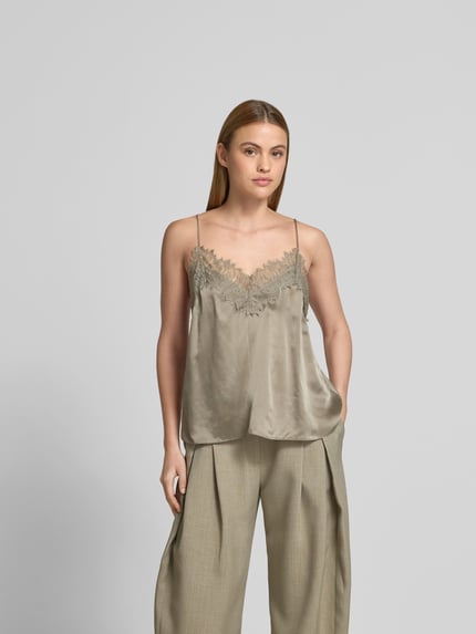 Frauenmodel trägt Bluse aus Satin mit Spitzenbesatz von Iro in Beige mit V-Ausschnitt, Spaghettiträgern und körpernaher Passform, Ganzkörperansicht von vorne.