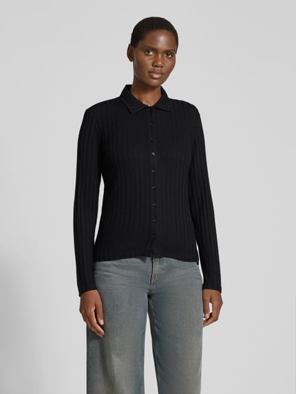 Frauenmodel trägt Cropped Langarmshirt mit durchgehender Knopfleiste Modell 'Sitami' von OPUS in schwarzer Melange-Strickoptik, Regular Fit, Strukturmuster, Hemdkragen, Knopfdetails, Rippstrick-Feinstrick, Ganzkörperansicht von vorne.