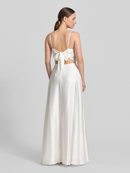 Frauenmodel trägt Abendkleid mit Spaghettiträgern von Laona in A-Linie als Maxikleid mit Reißverschluss auf der Rückseite, Rückenlänge 111 cm, Brustweite 41 cm, weiß, glatte seidige Textur, Ganzkörperansicht Rückansicht.