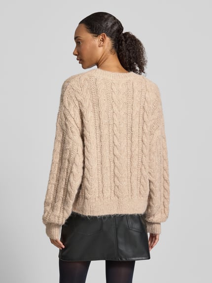 Frauenmodel trägt Oversized Fit Strickpullover mit Zopfmuster von REVIEW in Beige, grobe Strickstruktur, Ganzkörperansicht Rückansicht.