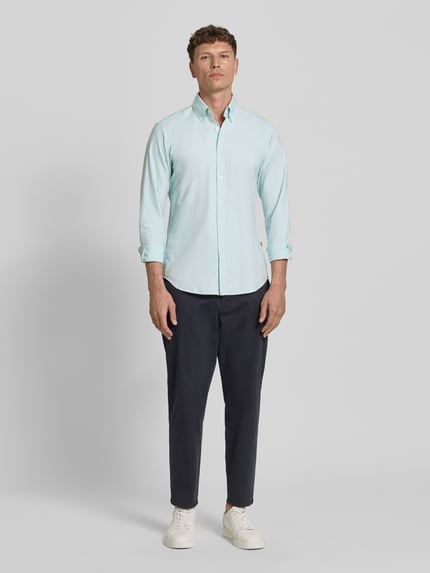 Männermodel trägt Regular Fit Freizeithemd aus reiner Baumwolle Modell 'RICKERT' von BOSS Orange in Hellblau, Ganzkörperansicht von vorne.