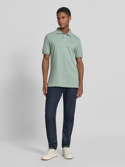 Męski model nosi Regular Fit Poloshirt aus reiner Baumwolle von s.Oliver RED LABEL, efekt: jednolity kolor, krój regular fit, wyhaftowane logo, kołnierzyk polo, dekolt w serek, listwa guzikowa, krótki rękaw, zakończenie rękawów prążkowane, wykończenie z rozcięciami po bokach, wykończenie materiału: pika, materiał: bawełna, całopostaciowy widok z przodu.