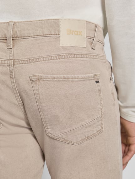 Männermodel trägt beigefarbene Slim Fit Jeans aus Baumwoll-Mix Modell 'Chuck' von Brax, Herren Slim Fit Jeans, Nahaufnahme Rückansicht