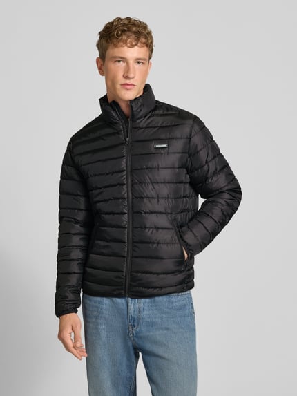 Männermodel trägt schwarze Jacke mit Label-Patch Modell 'ELVIS' von JACK & JONES, Reißverschluss, seitliche Taschen, Ganzkörperansicht von vorne.