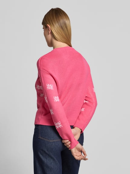 Frauenmodel trägt Pullover mit Pailletten-Schriftzug von VERO MODA in Pink mit Sternenmuster, Strickoptik, gerippte Abschlüsse, Ganzkörperansicht Rückansicht.