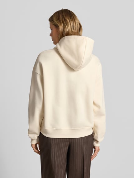Männermodel trägt Relaxed Fit Hoodie aus Mieszanka bawełny Model 'Iconic' von Gina Tricot w kolorze jasnym, gładka faktura, Ganzkörperansicht Rückansicht.
