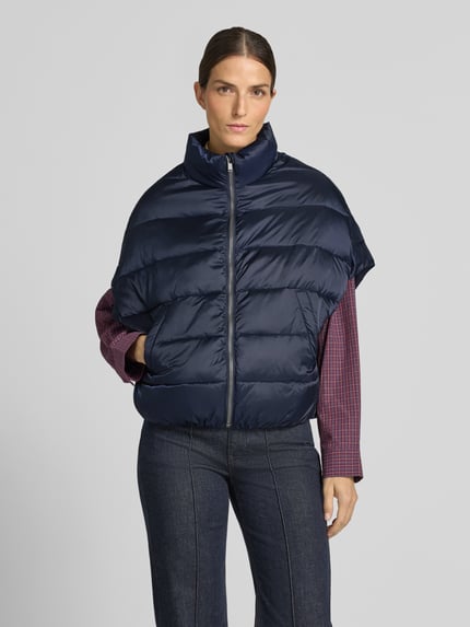 Frauenmodel trägt Steppweste mit Stehkragen und Eingrifftaschen von Milano Italy in Dunkelblau, glatte, gesteppte Textur, Ganzkörperansicht von vorne, Relaxed Fit, Reißverschluss, Rückenlänge 59 cm, Schulterbreite 50 cm, Brustweite 63 cm.