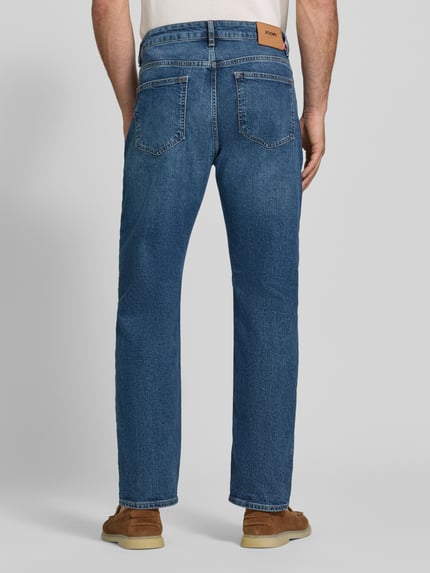 Männermodel trägt Straight Fit Jeans aus Baumwoll-Mix Modell 'Ray' von JOOP! in Blau, strukturierte Oberfläche, Ganzkörperansicht Rückansicht. Herren Straight Fit Jeans von JOOP! JEANS