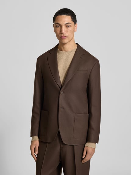 Männermodel trägt Regular Fit Sakko aus reiner Schurwolle von Officine Générale in Braun mit Reverskragen, Ganzkörperansicht von vorne. Rückenlänge 73 cm, Schulterbreite 46 cm, Ärmellänge 62 cm, aufgesetzte Eingrifftaschen und Knopfverschluss.