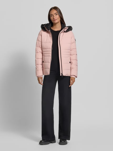 Frauenmodel trägt Jacke mit abnehmbarer Kapuze Modell 'ECLIPSE' von NAUTGÅRD in Rosa mit Zweiwege-Reißverschluss, Ganzkörperansicht von vorne. Rückenlänge 65 cm, Schulterbreite 41 cm, Brustweite 51 cm, Ärmellänge 64 cm, seitliche Eingrifftaschen, gestrickte Ärmelabschlüsse, Label-Patch.