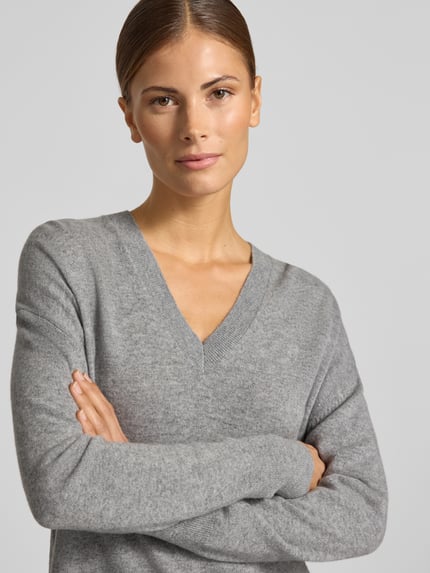 Frauenmodel trägt Pullover aus Wolle mit V-Ausschnitt von JAKE*S WOMAN CASUAL, graue Melange-Optik, Feinstrick, Nahaufnahme Oberkörper.