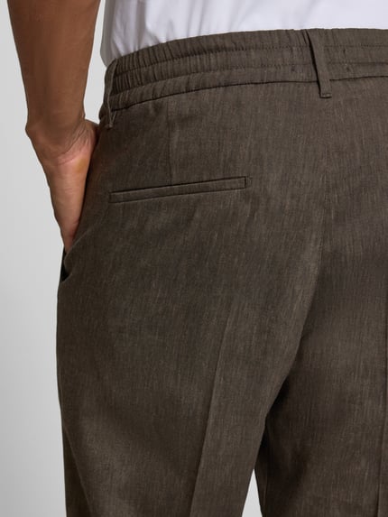 Männermodel trägt Hose mit Bügelfalte und elastischem Bund Modell 'CHASY' von Drykorn, Leinen-Mix mit Viskose-Anteil, Slim-Fit, Detailaufnahme Rückansicht, sichtbare Gesäßtasche und Bund.