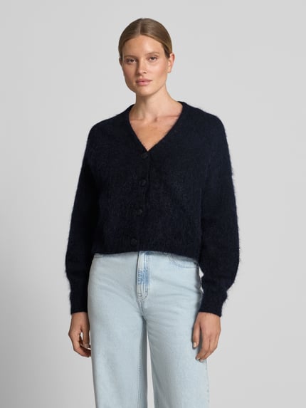 Frauenmodel trägt Oversized Wolljacke mit Woll- und Mohair-Anteil Modell 'Debbie' von Gestuz in Fell-Optik, V-Ausschnitt, Ganzkörperansicht von vorne. Elastischer Material-Mix, durchgehende Knopfleiste, elastische Ärmelenden, dunkelblaue Farbe, weiche Textur. Rückenlänge bei Größe S: 52 cm, Ärmellänge: 69 cm.
