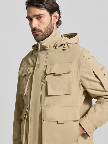 Männermodel trägt Oversized Funktionsjacke mit abnehmbarer Kapuze Modell 'BALTERO2611' von HUGO, unifarben, wasserabweisend, Nahaufnahme Oberkörper.