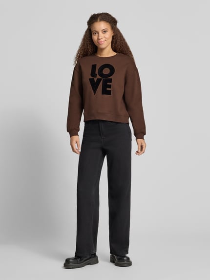 Vrouwenmodel draagt donkerbruin sweatshirt met LOVE frontprint, ronde hals, lange mouwen, elastische mouwboorden, model 'BRISA' van Pepe Jeans, Applicatie: motiefprint, dames sweatshirt, Ganzkörperansicht von vorne.