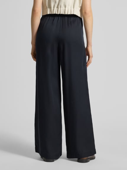 Frauenmodel trägt Wide Leg Stoffhose mit elastischem Bund von Lanius aus Lyocell, Eingrifftaschen, dunkel, Ganzkörperansicht Rückansicht.