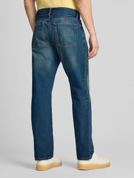 Männermodel trägt Relaxed Straight Fit Jeans im Used-Look von GAP aus bawełna mit wpuszczane kieszenie, szerokość w rozmiarze 32/32: 45 cm, długość wewnętrzna nogawki 80 cm, intensywny niebieski, prosty krój, efekt znoszenia, całkowity widok z tyłu.