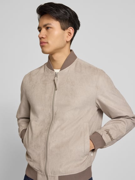 Männermodel trägt Bomberjacke in Leder-Optik mit Stehkragen von Jack & Jones, Beige- und Brauntöne, Reißverschluss, Nahaufnahme Oberkörper. Regular Fit, Eingrifftaschen, Rückenlänge 64 cm, Schulterbreite 45 cm, Brustweite 52 cm, Ärmellänge 67 cm.