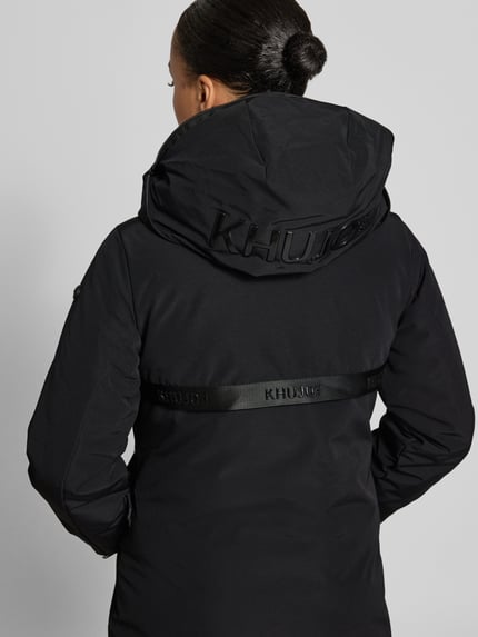 Frauenmodel trägt Steppmantel mit Label-Details Modell 'LOFI4' von khujo in Schwarz, strukturierte Oberfläche, Ganzkörperansicht Rückansicht.