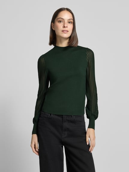 Frauenmodel trägt Strickpullover aus Viskose-Mix mit Stehkragen von zero, semitransparente Ärmel, dunkles Grün, Ganzkörperansicht von vorne.