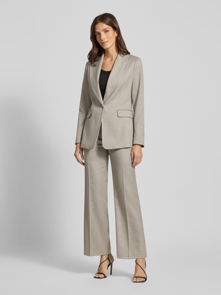 Frauenmodel trägt Slim Fit Longblazer aus Viskose-Mix von s.Oliver BLACK LABEL in hellgrauer Fischgrätoptik mit Reverskragen, Pattentaschen, Knopf mit Strasssteinbesatz, Ganzkörperansicht von vorne.
