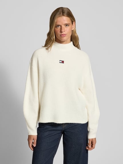 Frauenmodel trägt Relaxed Fit Pullover mit Alpaka-Anteil von Tommy Jeans in Creme mit feiner Strickstruktur, Ganzkörperansicht von vorne. Damen Pullover von Tommy Jeans
