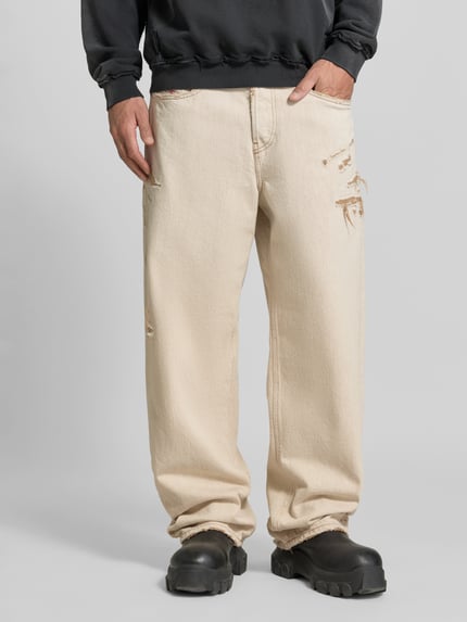 Männermodel trägt Straight Fit Jeans aus reiner Baumwolle von Diesel in Beige mit Destroyed Look, 5-Pocket-Design, Nahaufnahme Unterkörper.