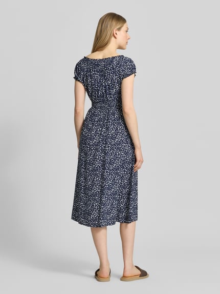 Modelka kobieca nosi 'Knielanges Kleid aus Viskose im Allover-Look' od Apricot w kolorze granatowym z białym wzorem, czysta wiskoza, krój dopasowany w talii, długość do kolan, okrągły dekolt, długość pleców w rozmiarze S 106 cm, szerokość w rozmiarze S 43 cm, długość rękawa w rozmiarze S 11 cm, widok całej sylwetki z tyłu.