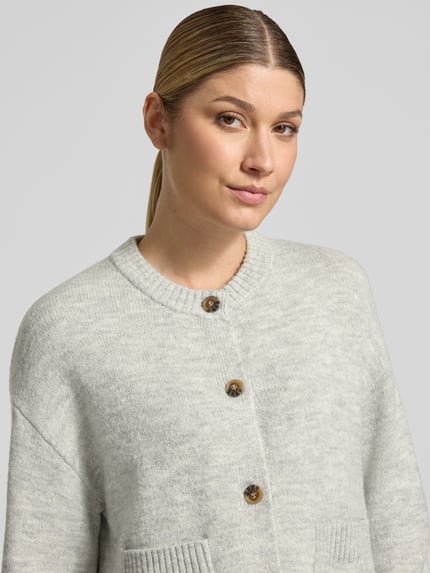 Frauenmodel trägt Cardigan mit aufgesetzten Taschen von Christian Berg Woman in unifarbener Strickoptik mit Struktur, Nahaufnahme Oberkörper.