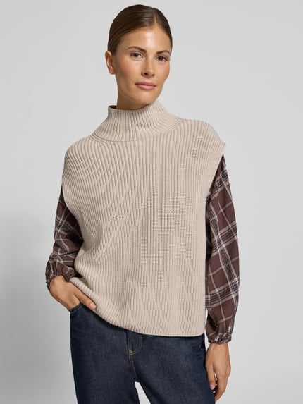Frauenmodel trägt Pullunder mit Mock Neck von MARC O'POLO in sandfarbenem Rippstrick mit Struktur und Strickoptik, Ganzkörperansicht von vorne.