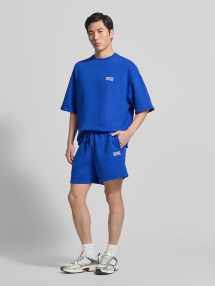 Männermodel trägt Shorts mit Logo Modell 'PLIZZY' von American Vintage aus Reine Baumwolle im Relaxed-Fit mit Tunnelzug, Ganzkörperansicht von vorne.