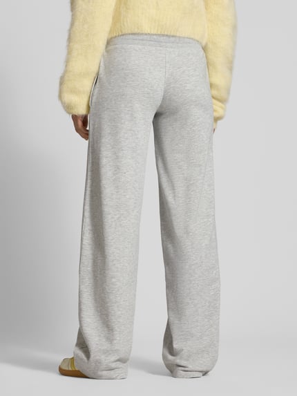 Frauenmodel trägt Wide Fit Sweatpants mit Viskose-Anteil von Review, hellgrau, elastischer Bund, Baumwoll-Mix, Ganzkörperansicht Rückansicht.