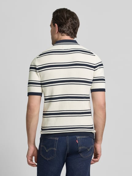 Männermodel trägt Slim Fit Poloshirt in Strick-Optik von MCNEAL, creme mit blauen Streifen, reine Baumwolle, Ganzkörperansicht Rückansicht.