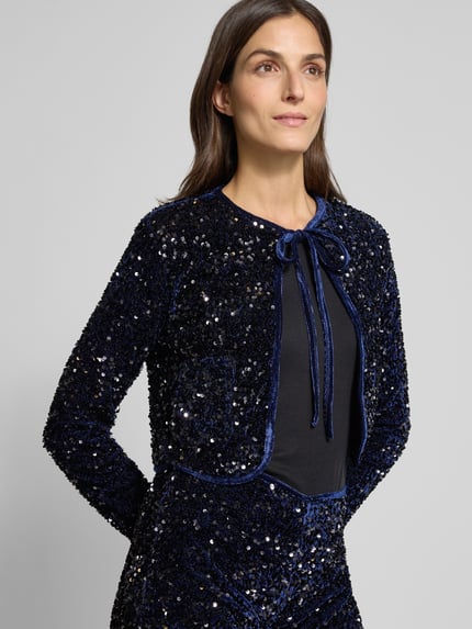 Frauenmodel trägt Bolero mit Pailletten und Schnürung Modell 'XTURNER' von Mango in dunklem Blau, cropped, Ganzkörperansicht von vorne.