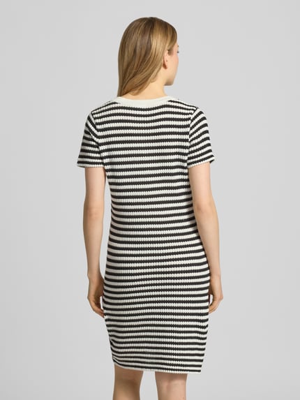Frauenmodel trägt knielanges Strickkleid mit V-Ausschnitt Modell 'LORIANNA' von ICHI, Schwarz-Weiß-Streifen, Baumwoll-Mix, körpernah, Ganzkörperansicht Rückansicht.