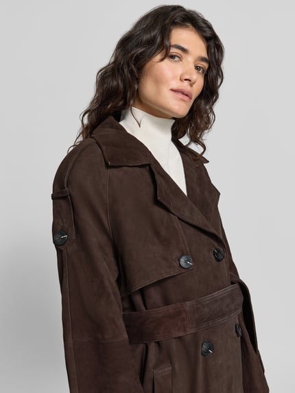 Frauenmodel trägt Mantel aus Lammvelours mit Bindegürtel von Cph Muse in Dunkelbraun, strukturierte Optik, Detailaufnahme Oberkörper.
