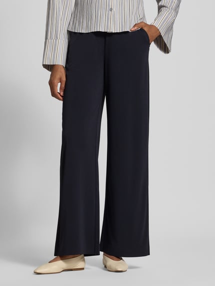 Frauenmodel trägt Relaxed Fit Stoffhose mit Tunnelzug von MM by Max Mara in Dunkelblau, mit Gürtelschlaufen und Eingrifftaschen, Nahaufnahme Unterkörper.
